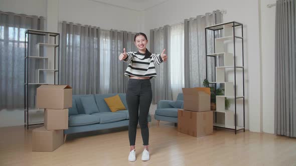 Asian Woman With Cardboard Boxes On The Floor Smiling And Showing Thumbs Up Gestures To Camera