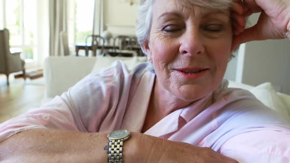 Portrait of smiling senior woman sitting on sofa in living room