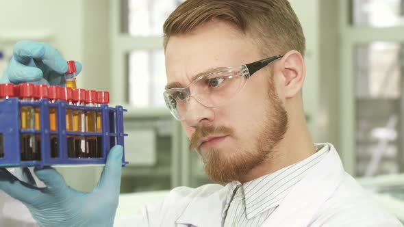 A Young Laboratory Worker Looks Carefully at Each Test Tube