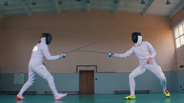 Two Young Women Having an Active Fencing Training in the School Gym