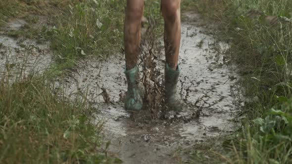 Close-up of Girl Legs in Boots Jumping in Very Muddy Puddle