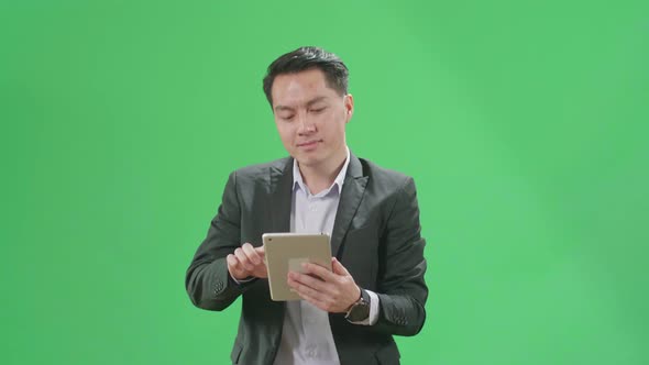 Asian Business Man Use Tablet While Walking On Green Screen Chroma Key