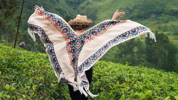 Young Woman Running At Tea Plantation Field Taking Off Her Poncho