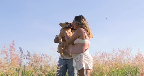 Couple Waiting for their first baby, playing with their pet, a french bulldog dog, happy family.