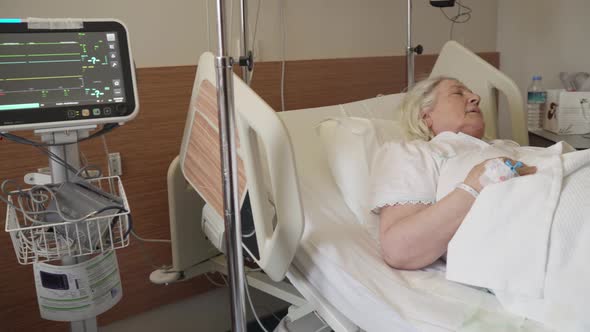 An old lady sleeping and resting on a bed in a hospital.