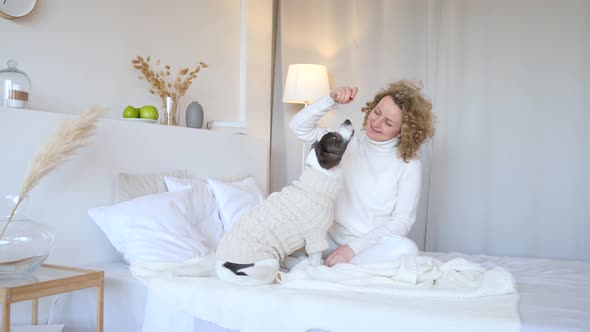 Young Woman Playing With Dog On Bed In Bedroom