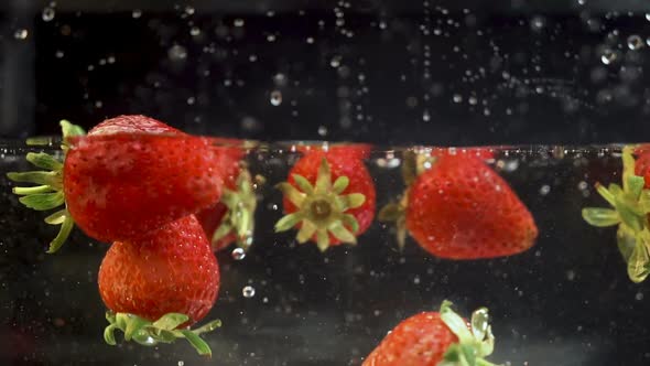 A couple of ripe strawberries getting into a liquid