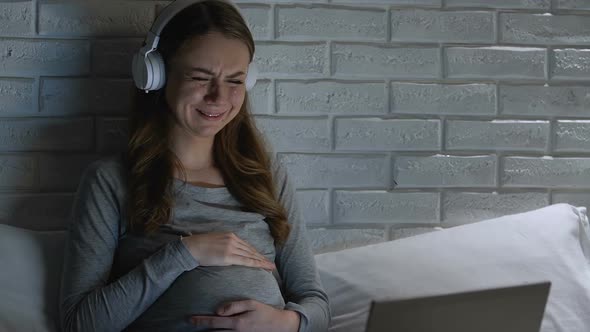 Crying Pregnant Woman in Headphones Watching Melodramatic Movie on Laptop