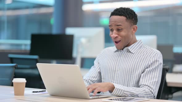 Successful African Businessman Celebrating on Laptop at Work