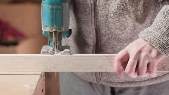 A Guy Cuts a Wooden Beam with a Jigsaw Closeup