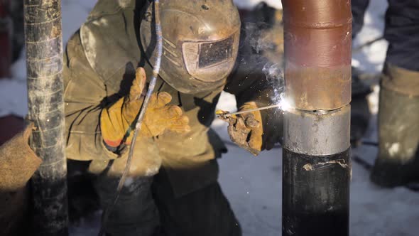 Worker Produces Pipe Welding on the Street. In Winter, at Low Temperatures, It Is Difficult To Mount