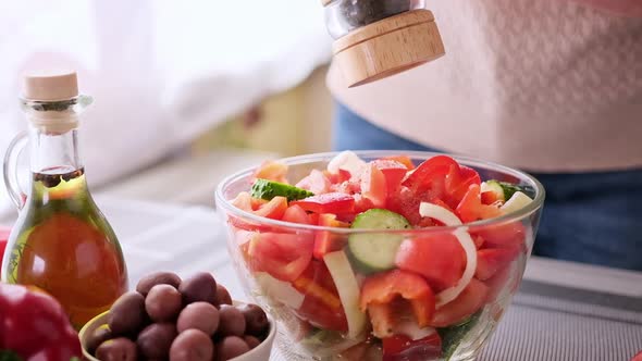 Greek Salad Preparation Series Concept  Woman Peppers Chopped Vegetables in a Glass Bowl