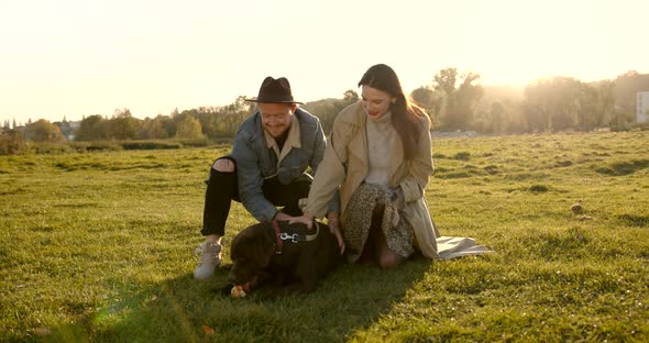 Young Couple Sitting Near a Dog in Nature