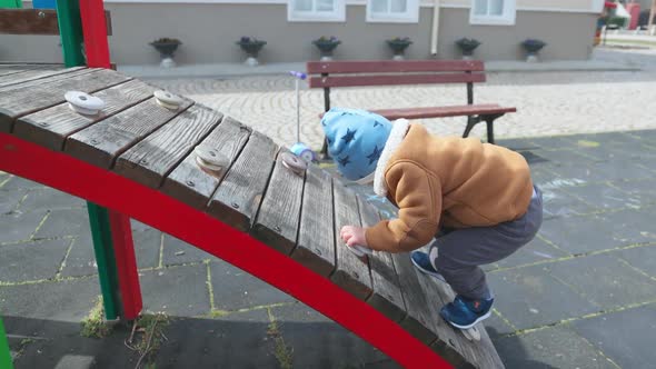 A Boy on a Playground in an Autumn Park Climbs a Hill in Cloudy Weather