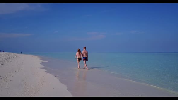 Teenage lovers in love on idyllic shore beach lifestyle by blue ocean and white sand background of t