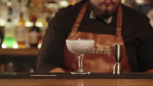 Bartender Is Filling Crystal Glass By White Mixed Drink and Decorating It