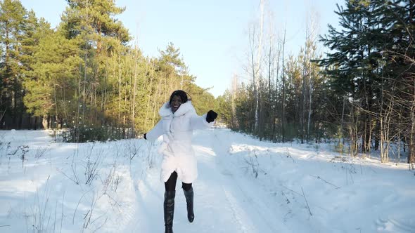 AfricanAmerican Girl Runs Along Snowy Path in Winter Forest