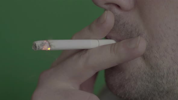 Cigarette in the Mouth of a Smoker. Close-up. Chroma Key. Green Background.