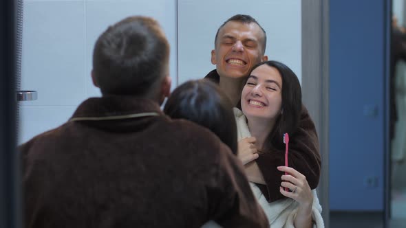 Happy Couple with Toothbrushes in Front of Mirror