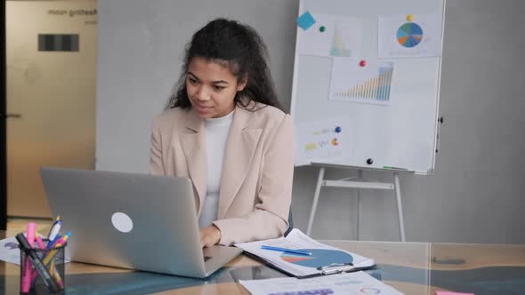 Smiling African American Female Businesswoman Analyzing the Business Report in the Office