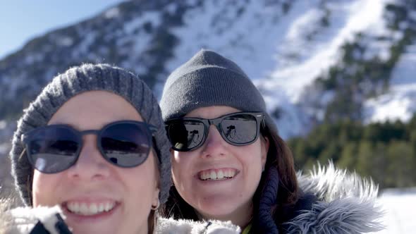 Young friends having fun doing selfie during winter vacation with mountain snow on background