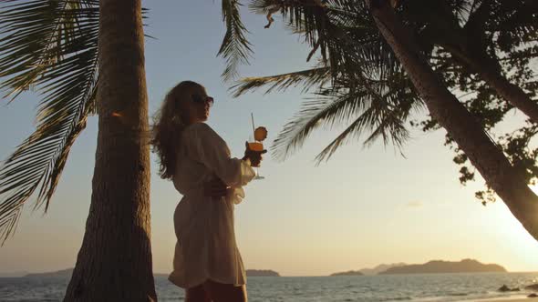 Woman Drinking Pineapple Cocktail Pina Colada Near Palm Tree in White Shirt Sunglasses