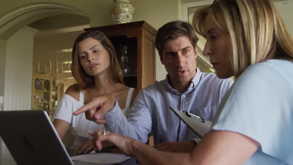 Caucasian couple and a senior Caucasian woman sitting on a couch in an apartment