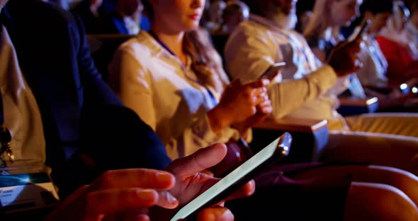 Multi-ethnic business people using mobile phone during business seminar in auditorium 4k