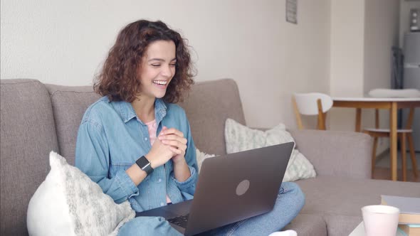 Hispanic Young Woman Using App on Laptop Computer While Sitting at Home