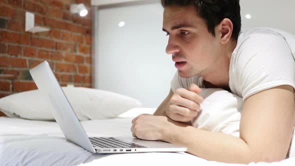 Sick Man Coughing while Working on Laptop in Bed