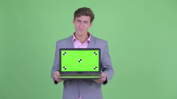 Stressed Young Businessman Showing Laptop