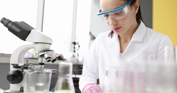 Young Woman Scientist Wipes Table and Microscope with Napkin