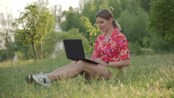 A Middleaged Woman Works Using Her Laptop in a Public Park