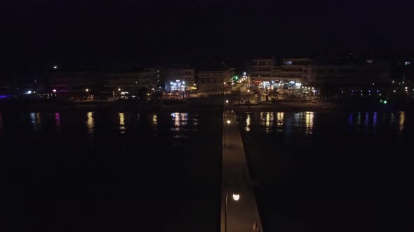 Aerial flight above the sea moving away from coast line with resort district in Greece