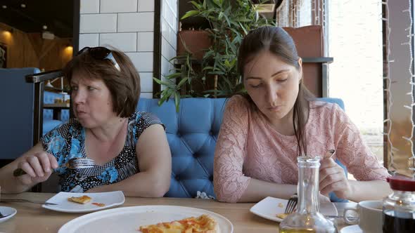 Woman and a Girl are Having Dinner at a Cafe Eating Pizza