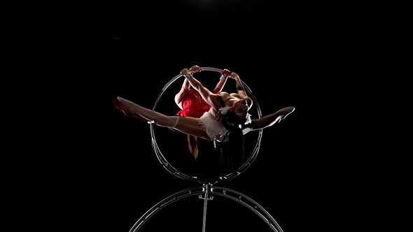 Girls Air Acrobats Rotate in the Air While on a Metal Hoop. Black Background. Slow Motion