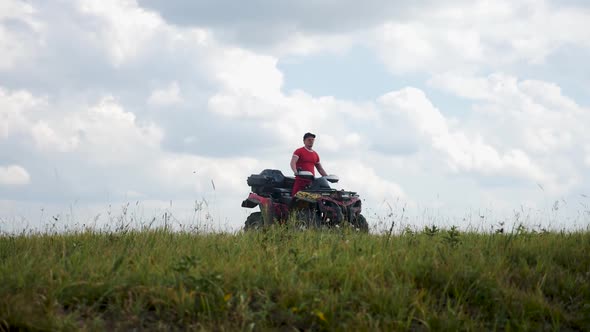 Man in a Black Cap and Red T-shirt on a Colored ATV Rides