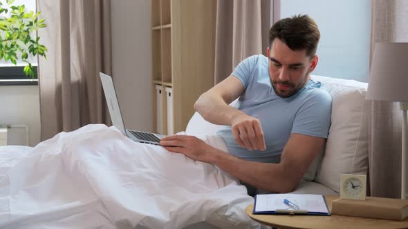 Man with Laptop in Bed at Home Bedroom