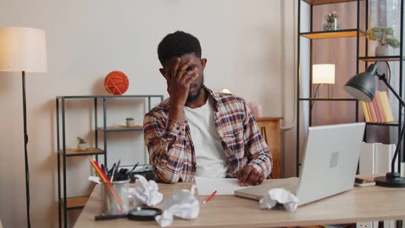 Sad Young Man Working at Home Office Crumples Throwing Heets of Paper with Bad Ideas and Mistakes