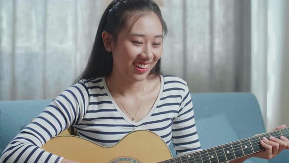Close Up Of Asian Woman Learning Playing Guitar By A Laptop At Home