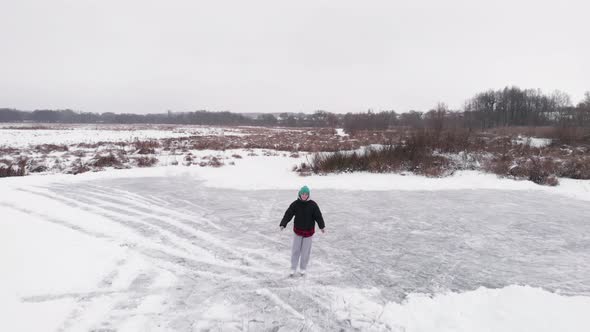 Young woman is ice skating on frozen lake