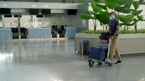 Man in Mask at Empty Airport at Check in in Coronavirus Quarantine Isolation Returning Home Flight