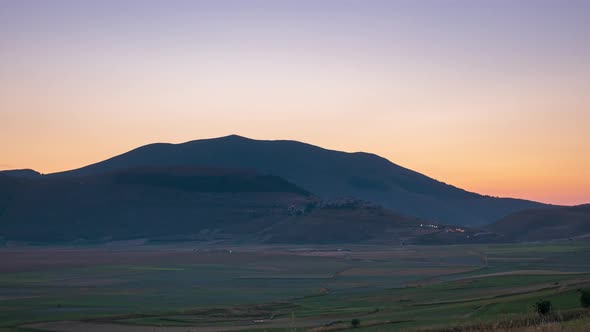 Time lapse: sunset over Castelluccio di Norcia highlands, Italy. The village perched on hill top ove