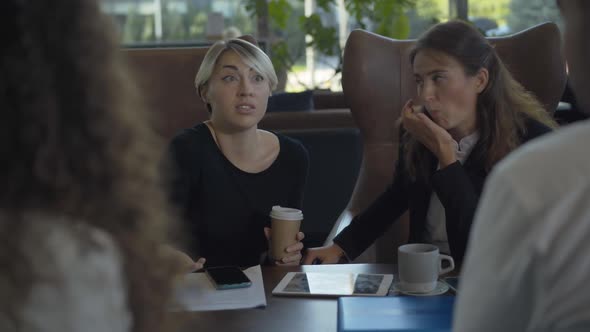 Portrait of Excited Caucasian Woman Sitting with Coworkers in Cafe and Talking. Positive Successful