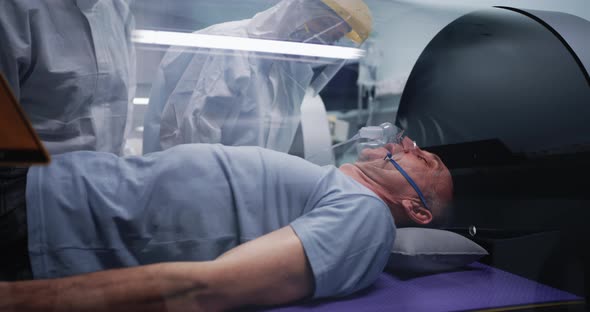 Doctors Discussing Aged Man in Hyperbaric Chamber