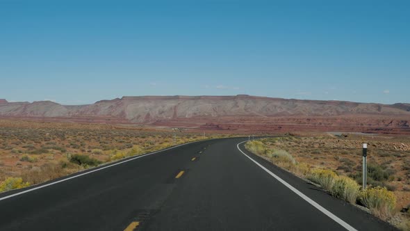 Driving On Highway Going Into Distance Through Desert On Background Of Red Rocks