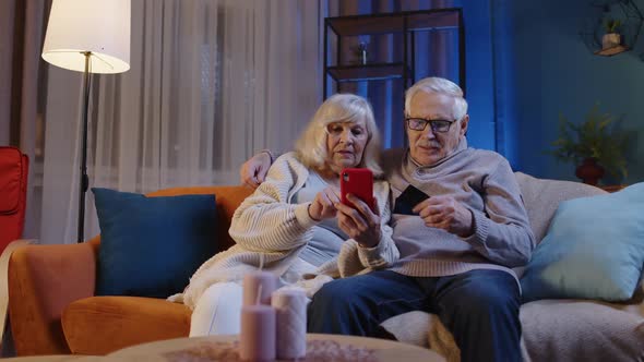 Senior Family Couple with Smartphone at Home Making Online Shopping with Credit Plastic Bank Cards