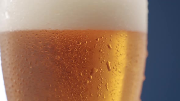 Close Up of Full Beer Mug with Lots of Foam and Drops on Glass in Rotation