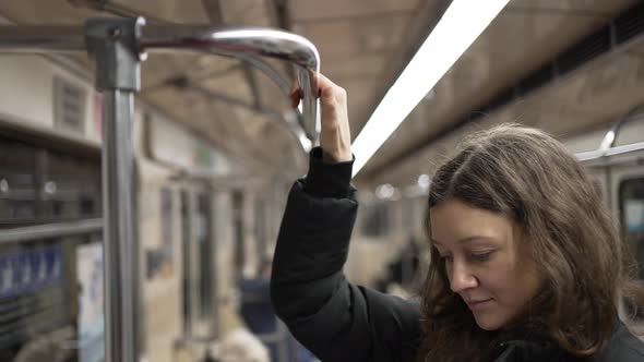 A Young Woman in a Subway Car Grabs the Handrail with Her Hand in Closeup