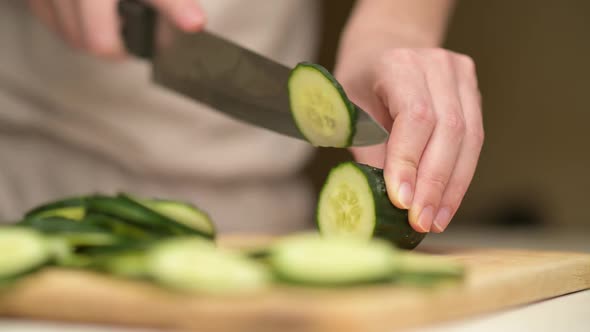 woman slicing a cucumber on a kitchen board